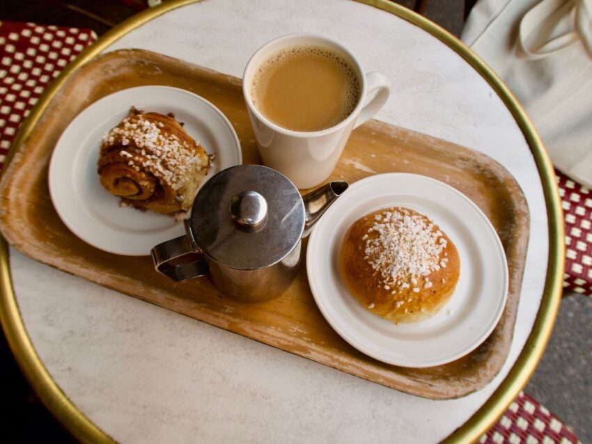 Kaffekopp, kaffekanna och två kanelbullar på ett serveringsfat
